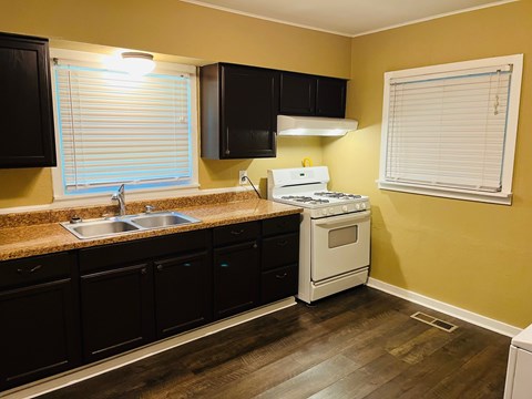 A kitchen with black cabinets and a white stove top oven.