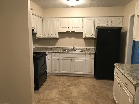a kitchen with white cabinets and black appliances