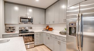 an updated kitchen with stainless steel appliances and white cabinets