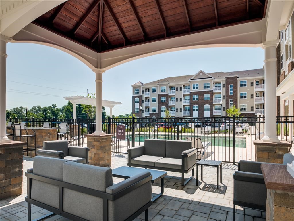 a covered patio with couches and tables with a building in the background
