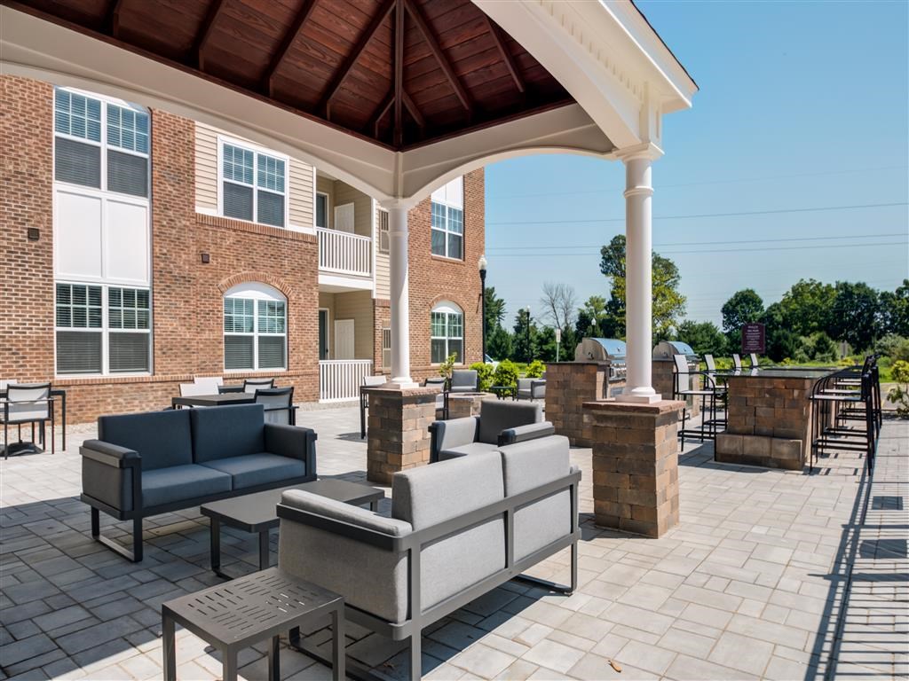 a covered patio with couches and tables in front of a building