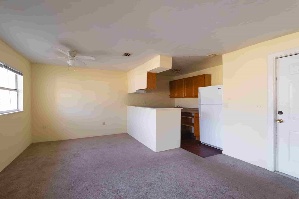 an empty kitchen with a refrigerator and a sink