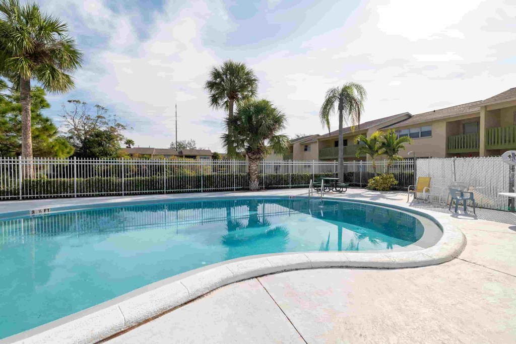 a swimming pool with palm trees and a building in the background