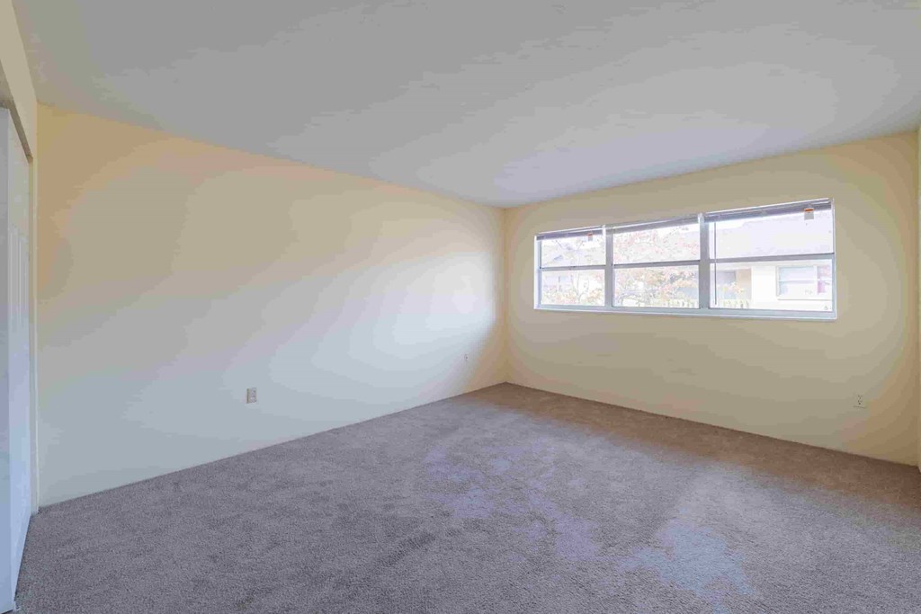 an empty room with white walls and a window