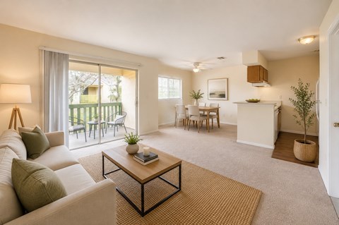 A living room with a white couch, a coffee table, and a dining area with chairs and a table.