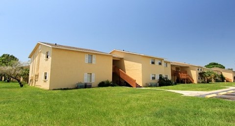 A yellow house with a brown staircase leading to the entrance.