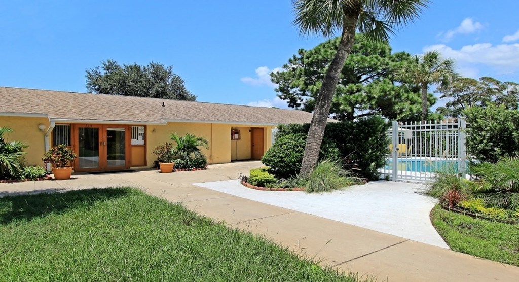 a house with a walkway and a gate and a palm tree
