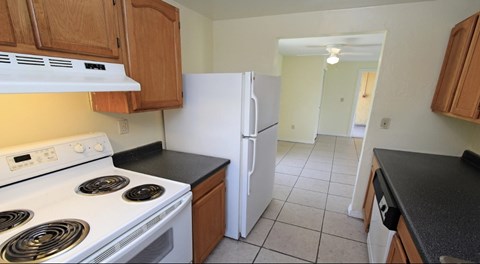 A kitchen with a white stove and a white refrigerator.