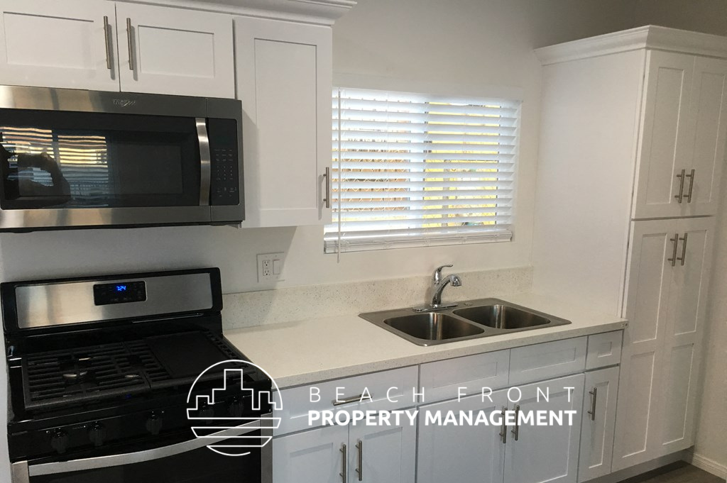 a kitchen with white cabinets and a sink and a microwave