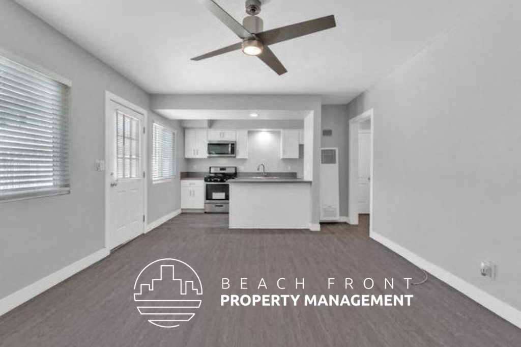 an empty living room with a ceiling fan and a kitchen