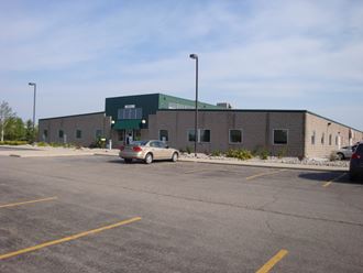 a large brick building with a parking lot and a car