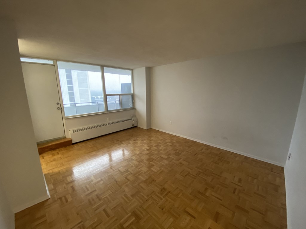 an empty living room with wooden floors and a window