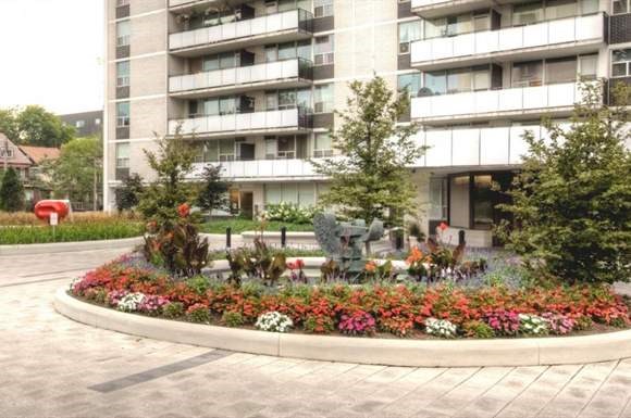 a round flower garden in front of an apartment building