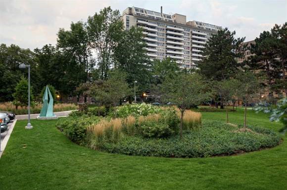 a park with a fountain and trees and a building