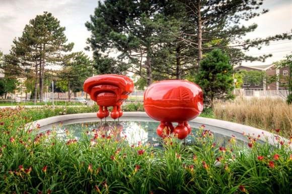 a fountain with two red balls in the grass