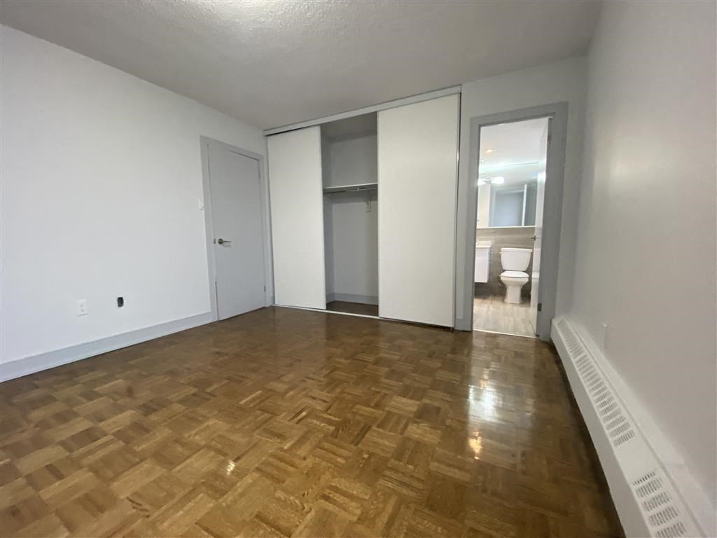 an empty living room with a hard wood floor and a closet