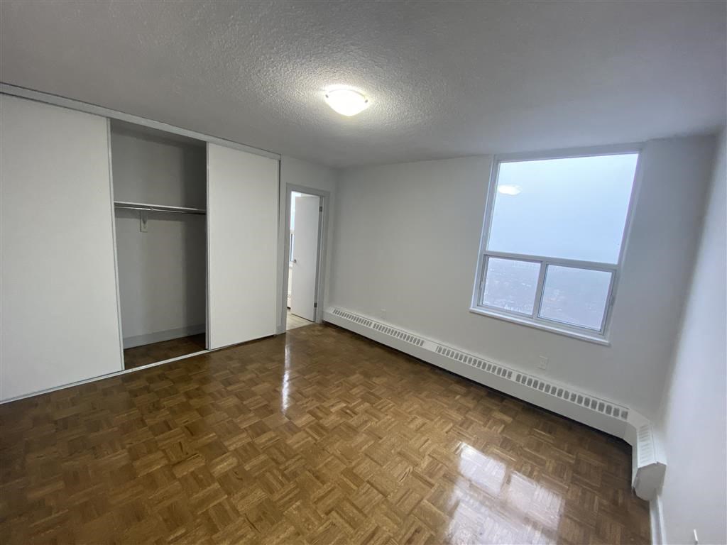 an empty living room with wood flooring and a window
