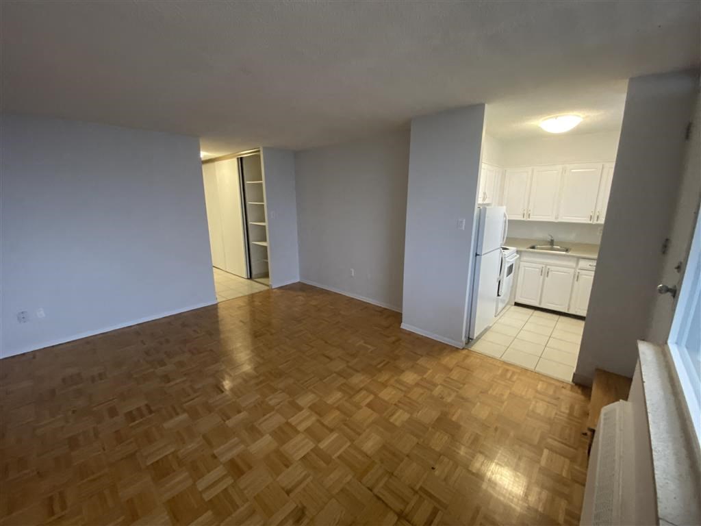 an empty living room and kitchen with a wood floor
