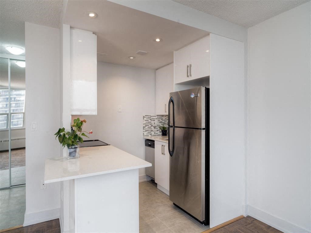 a white kitchen with a stainless steel refrigerator