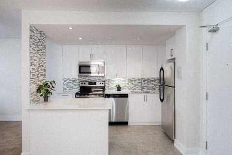 a white kitchen with white cabinets and a stainless steel refrigerator