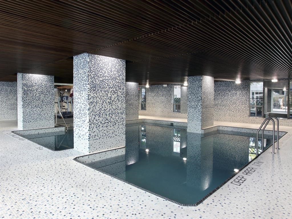 the indoor swimming pool of a building with pillars and a wooden ceiling