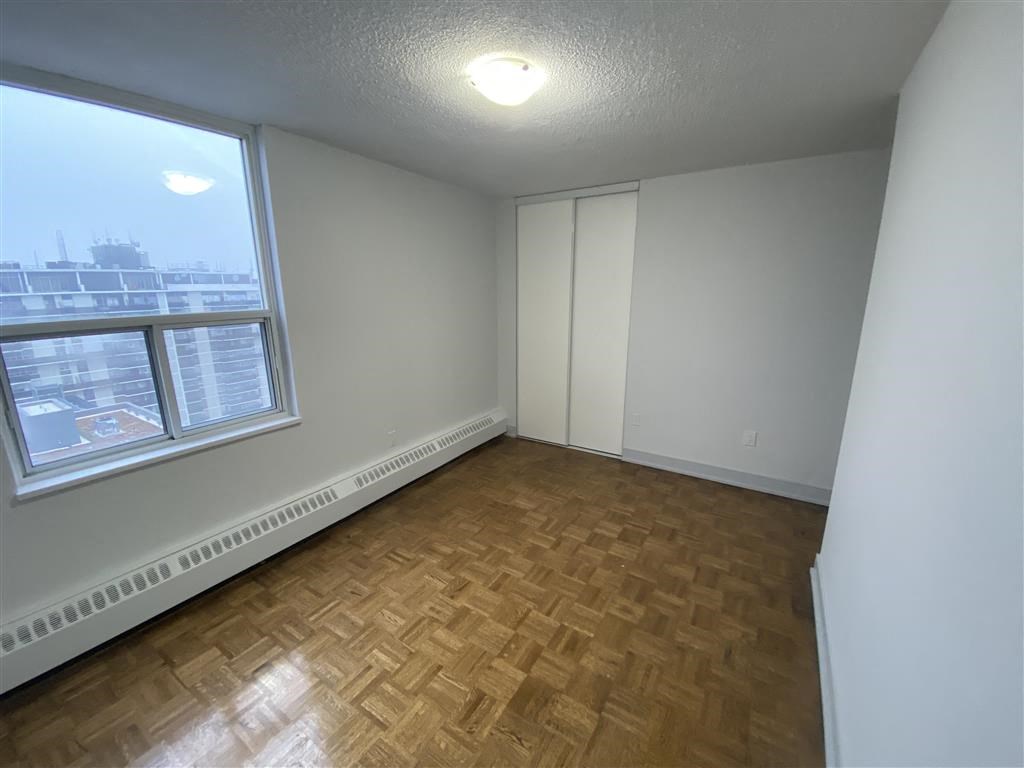 an empty living room with a large window and wooden floors