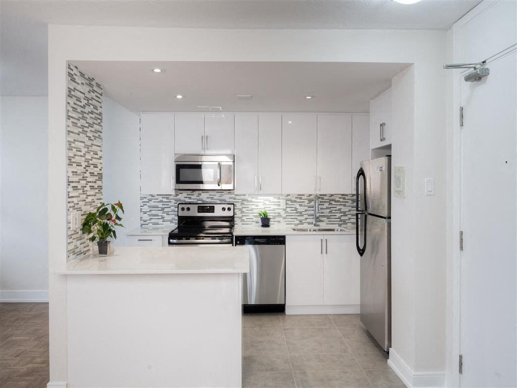 a white kitchen with stainless steel appliances and white cabinets