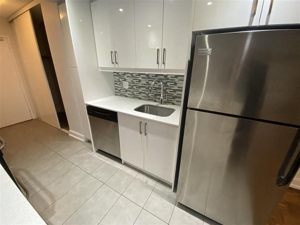a kitchen with a stainless steel refrigerator and white cabinets
