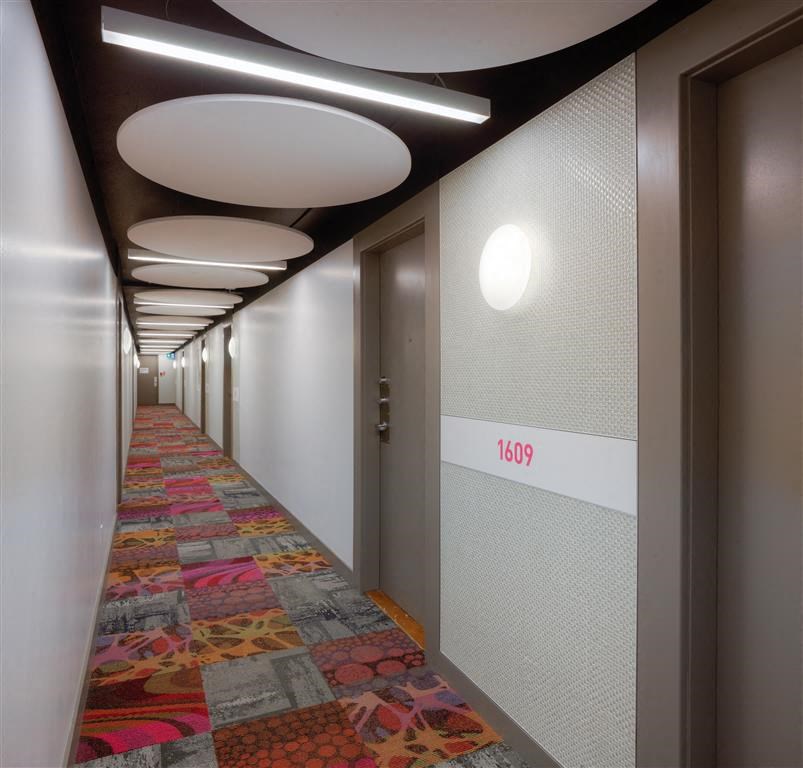 a long hallway with colorful quilted carpet and doors