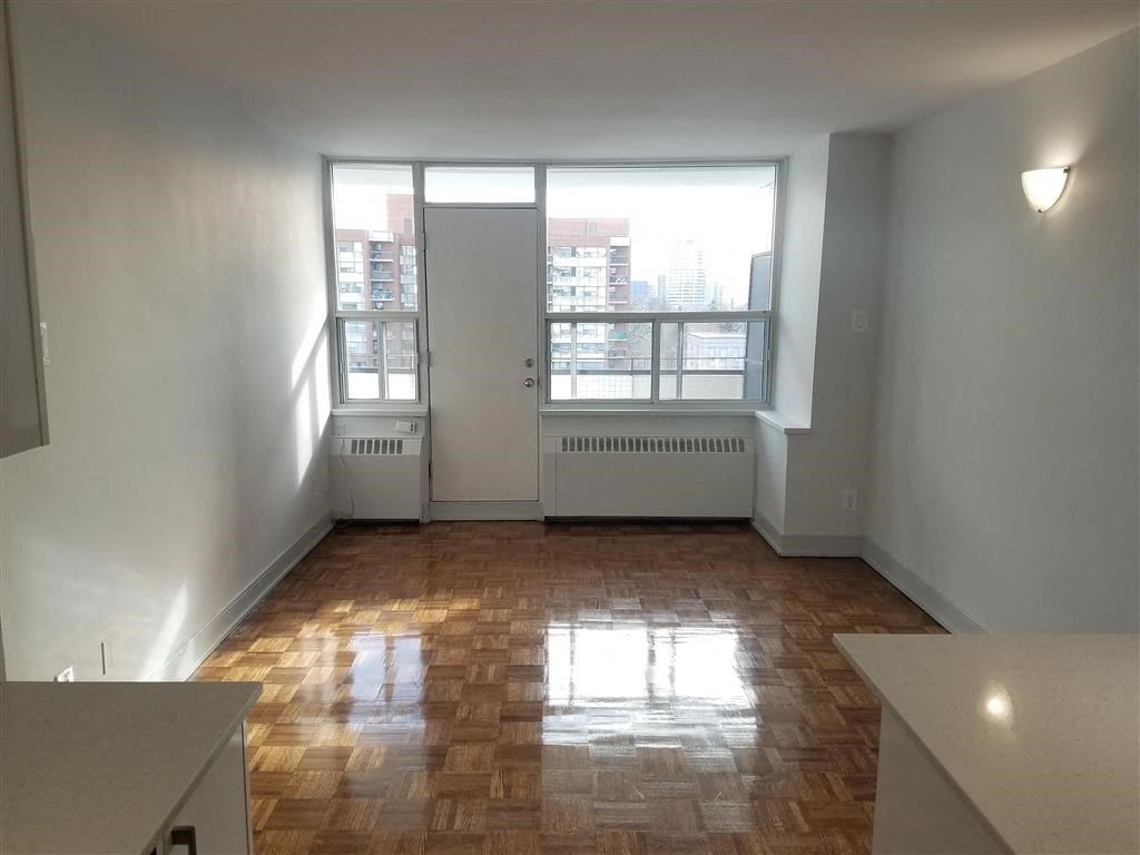 an empty living room with a window and wooden floors