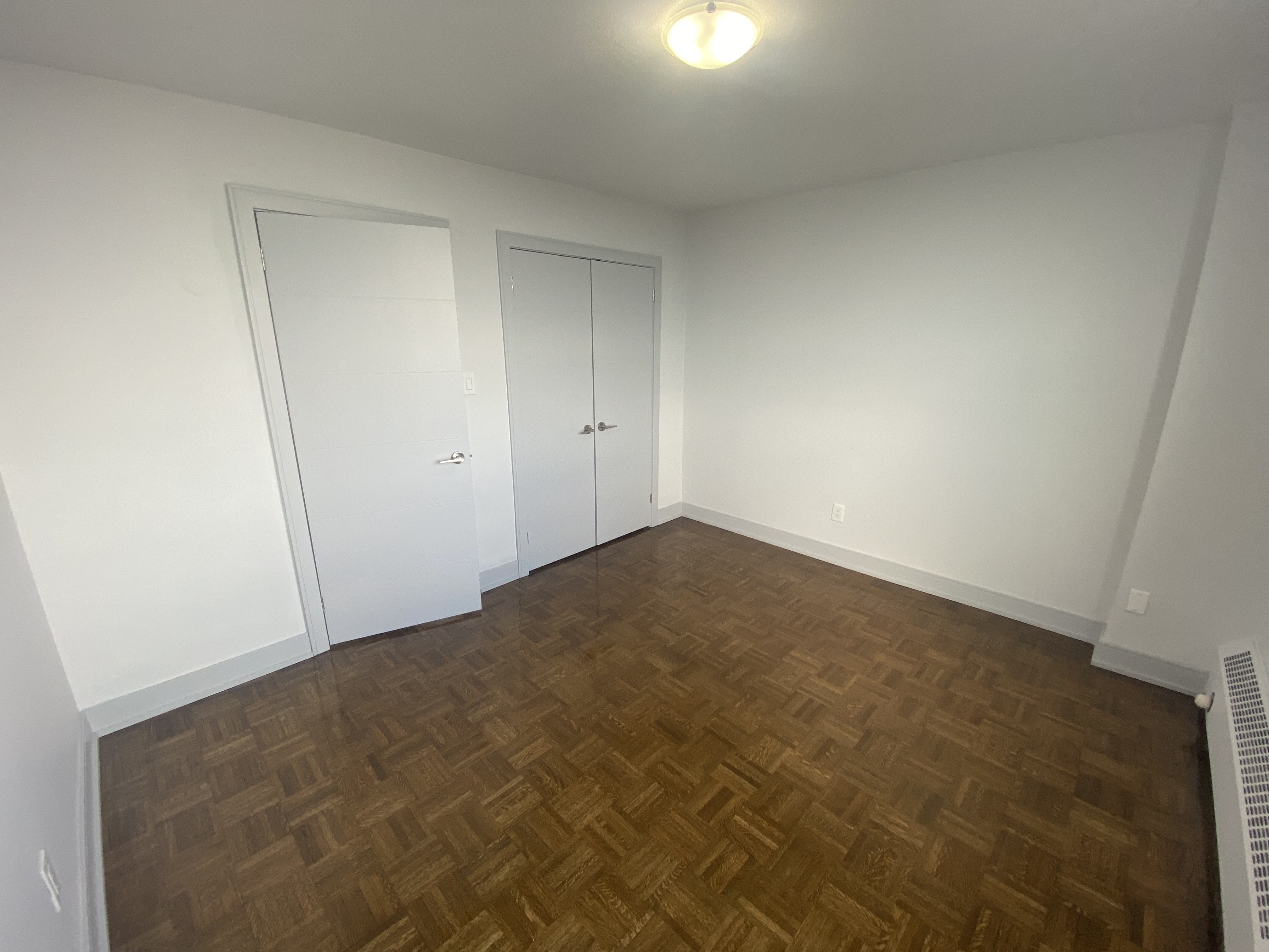a bedroom with wood flooring and white walls and doors