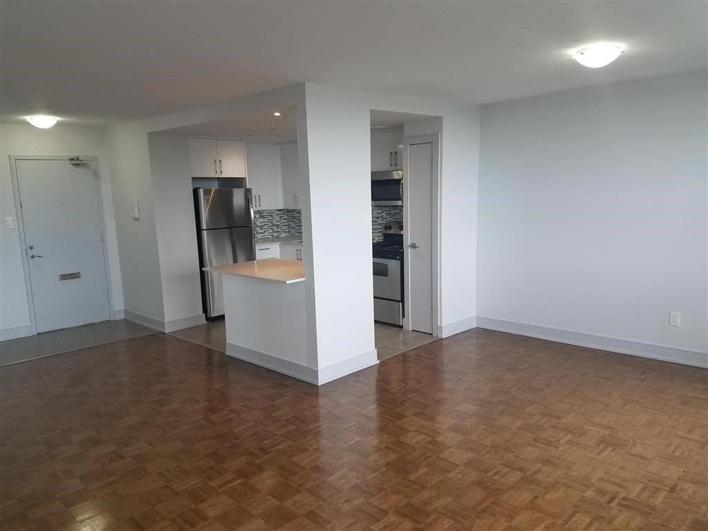 an empty living room and kitchen with a wood floor