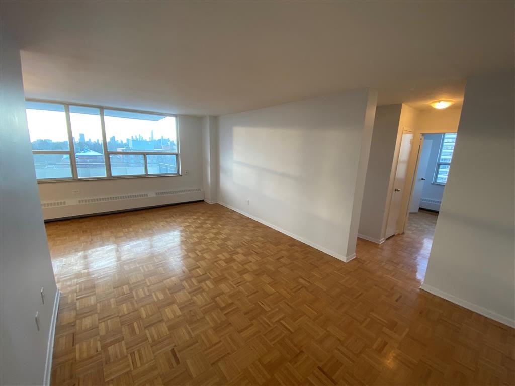 an empty living room with wood flooring and a window