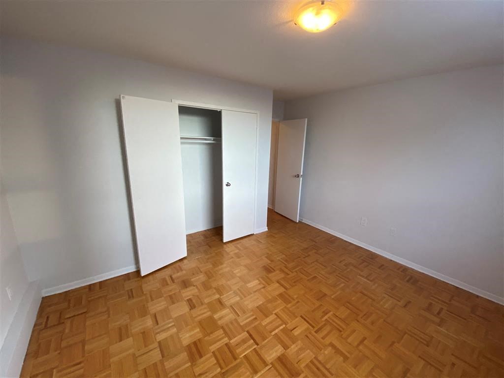 an empty living room with wood flooring and a closet