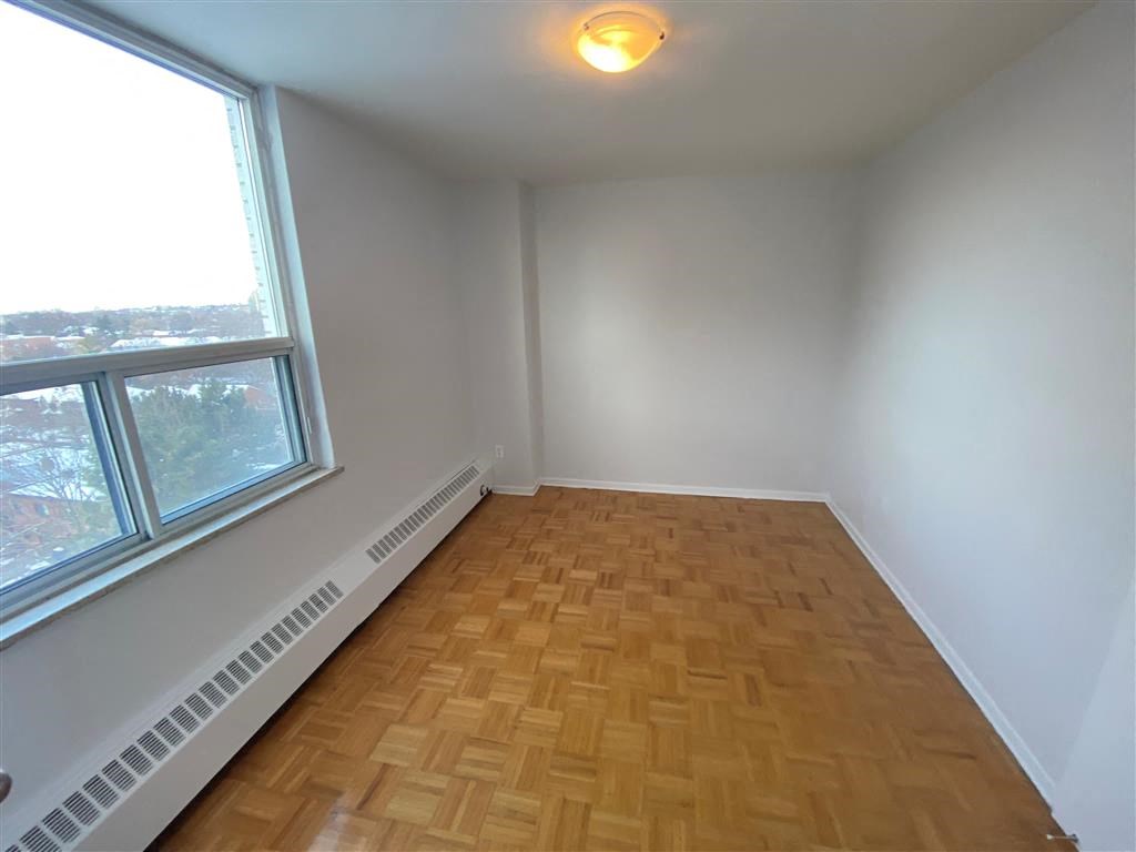 an empty room with a large window and wooden floors