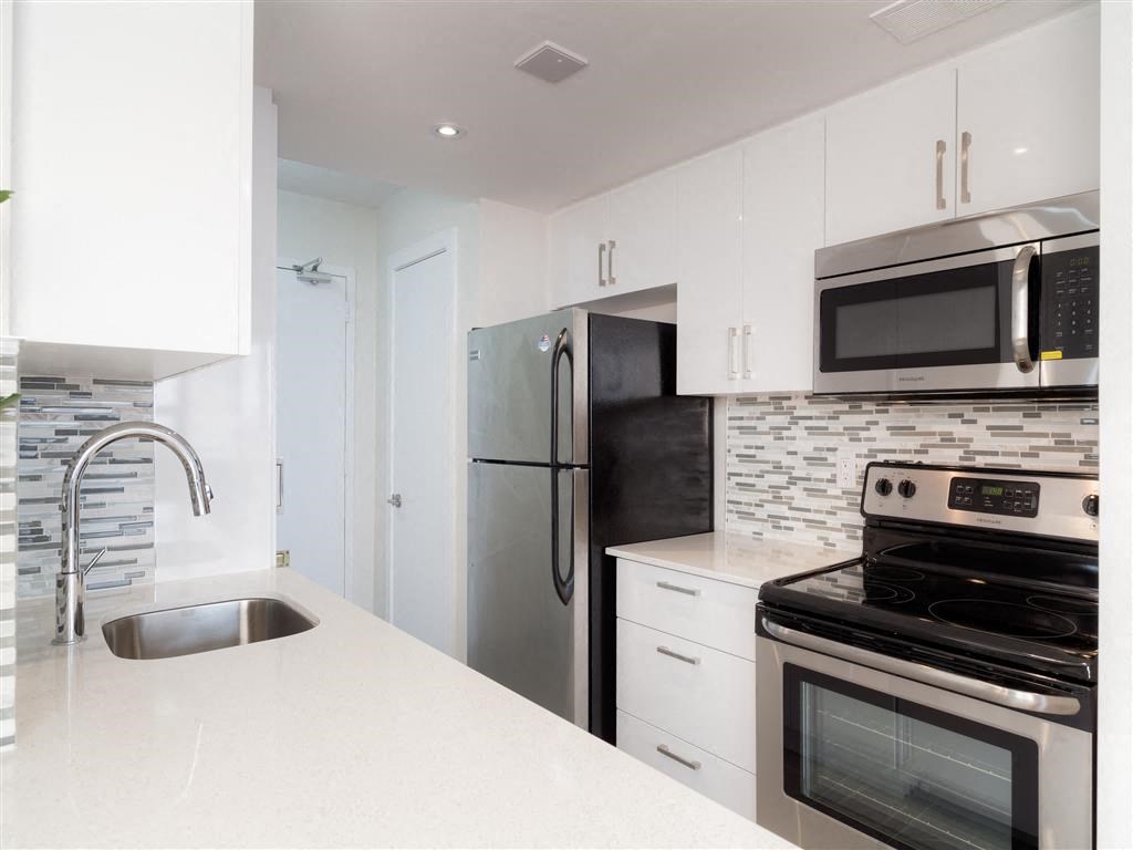 a white kitchen with stainless steel appliances and a sink