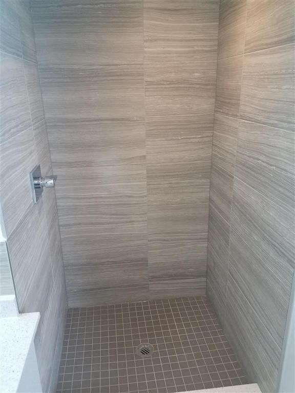 a bathroom with a shower with a tiled wall and floor