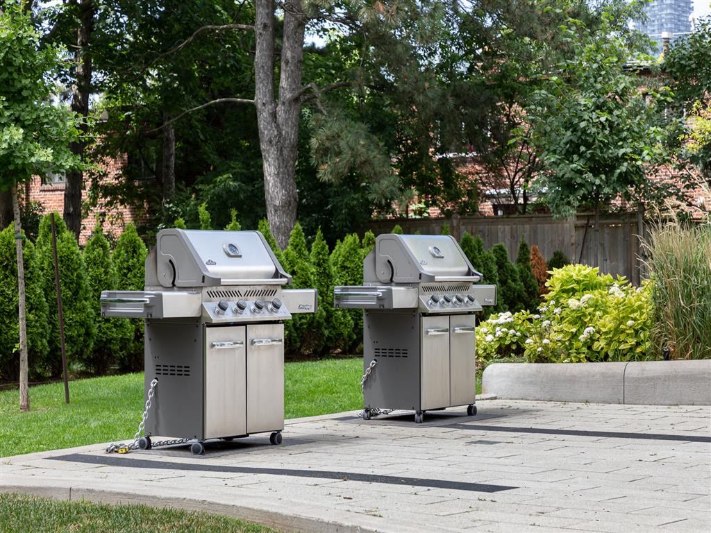 two stainless steel barbecue grills on a sidewalk