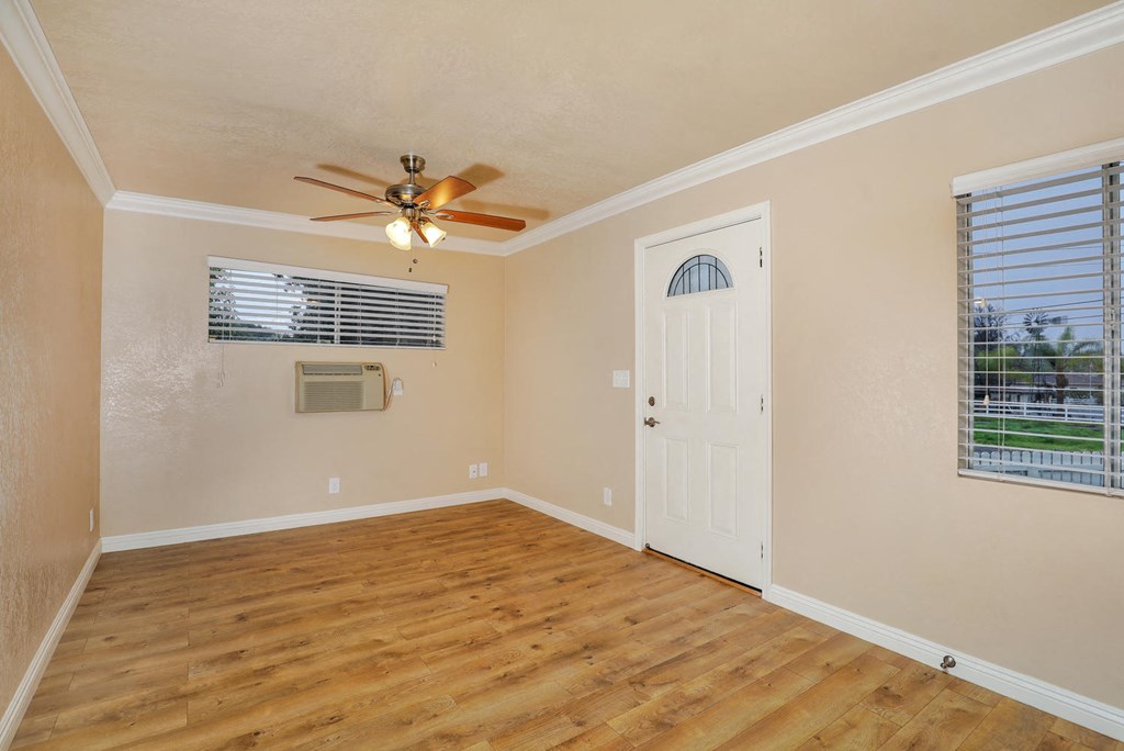 an empty living room with a ceiling fan and a door