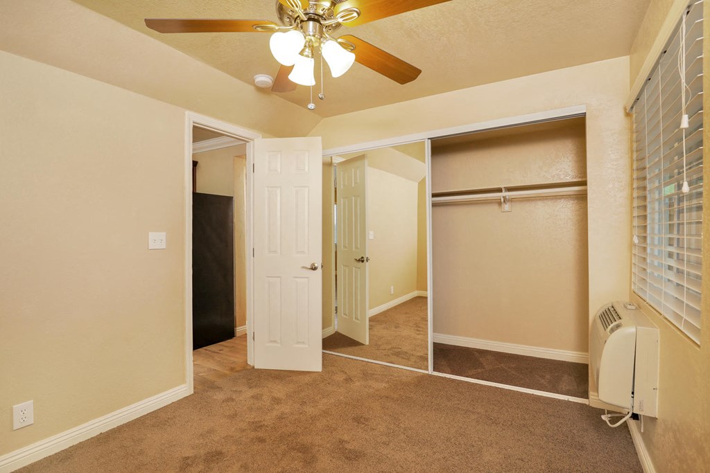 a bedroom with a ceiling fan and a closet