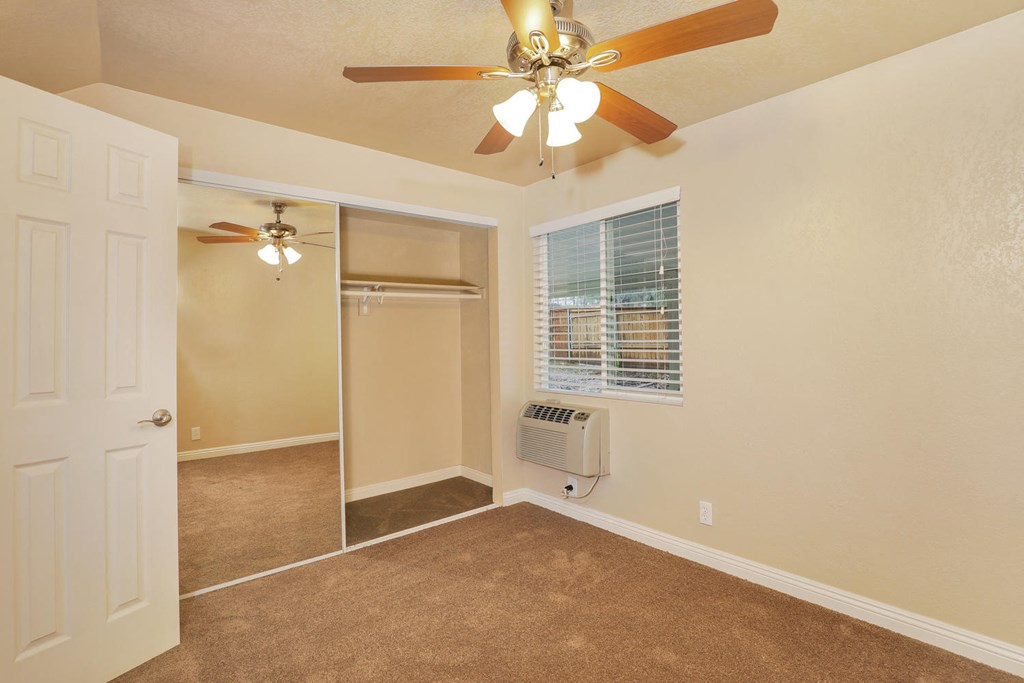 a bedroom with a ceiling fan and a closet