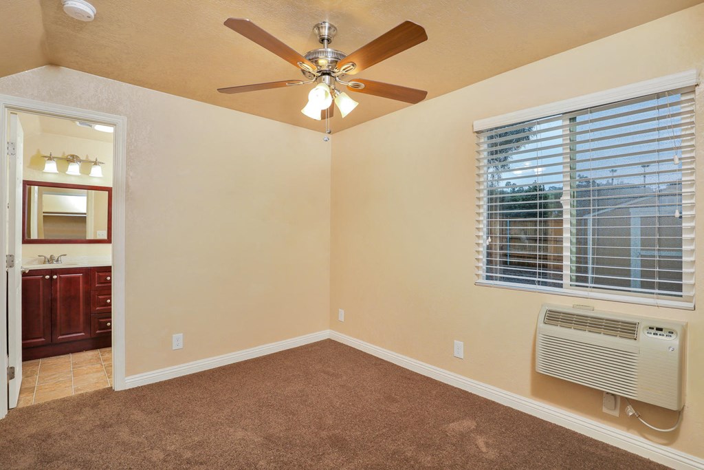 an empty bedroom with a ceiling fan and a window