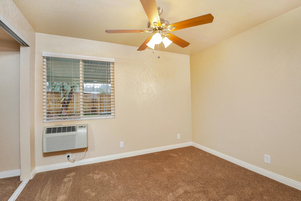 an empty living room with a ceiling fan and a window