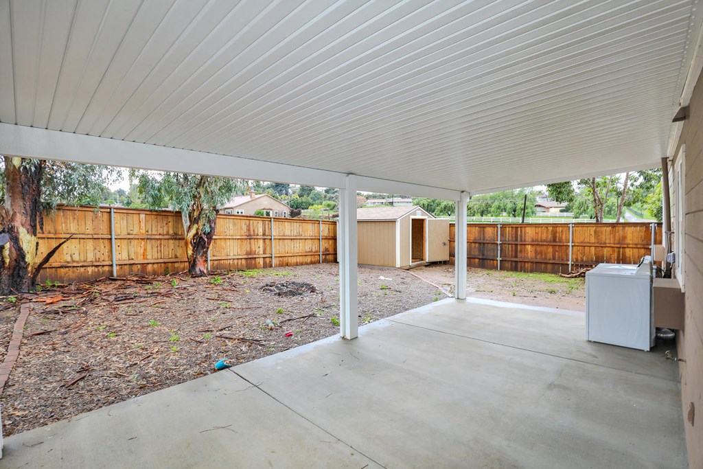 a covered patio with a yard and a wooden fence