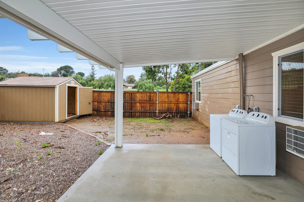 a patio with a washer and dryer on the side of a house