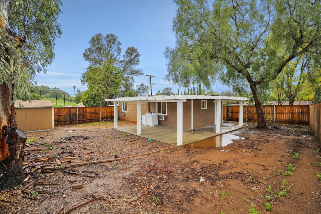 a small house with a dirt yard and trees