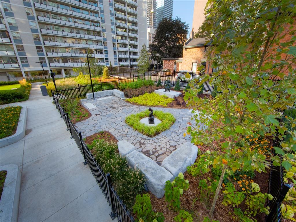 a garden with trees and plants and a sidewalk