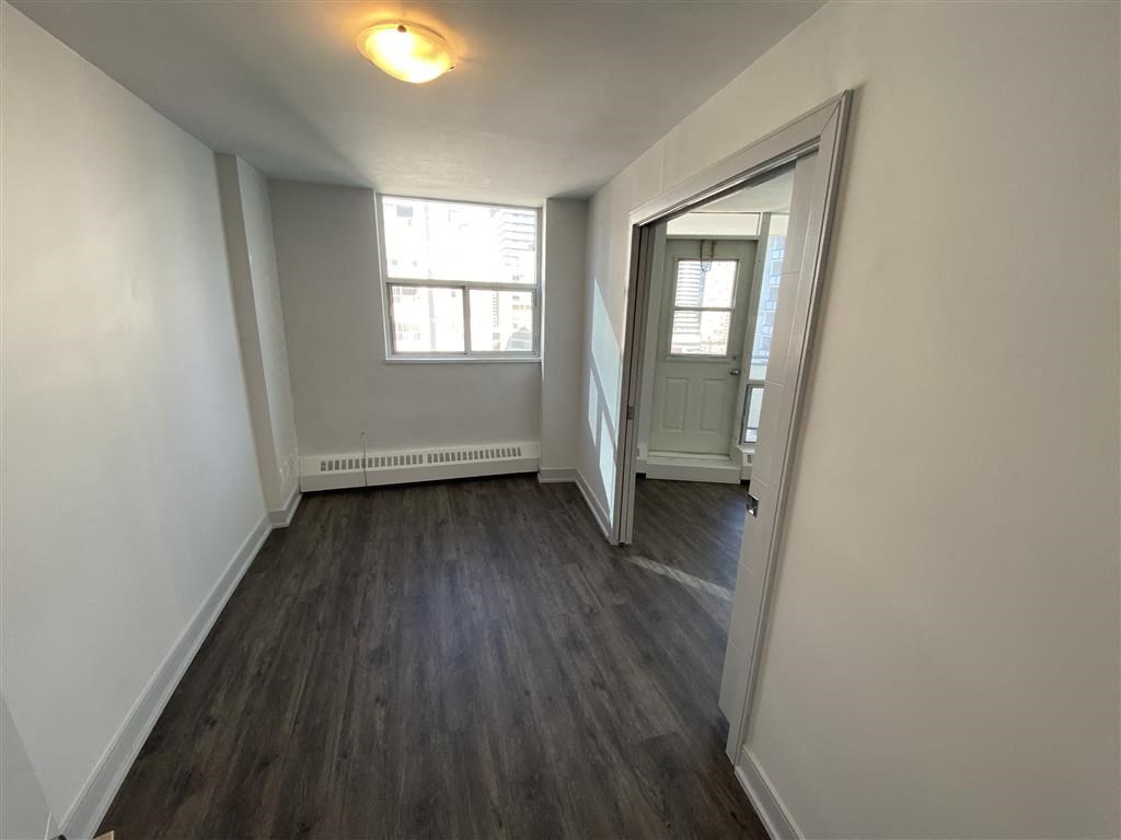 an empty living room with wood floors and a window