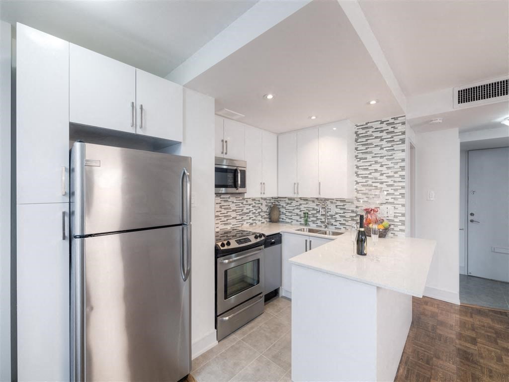 a white kitchen with stainless steel appliances and a counter top