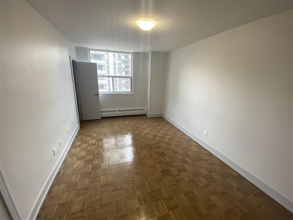 an empty living room with wood flooring and a window
